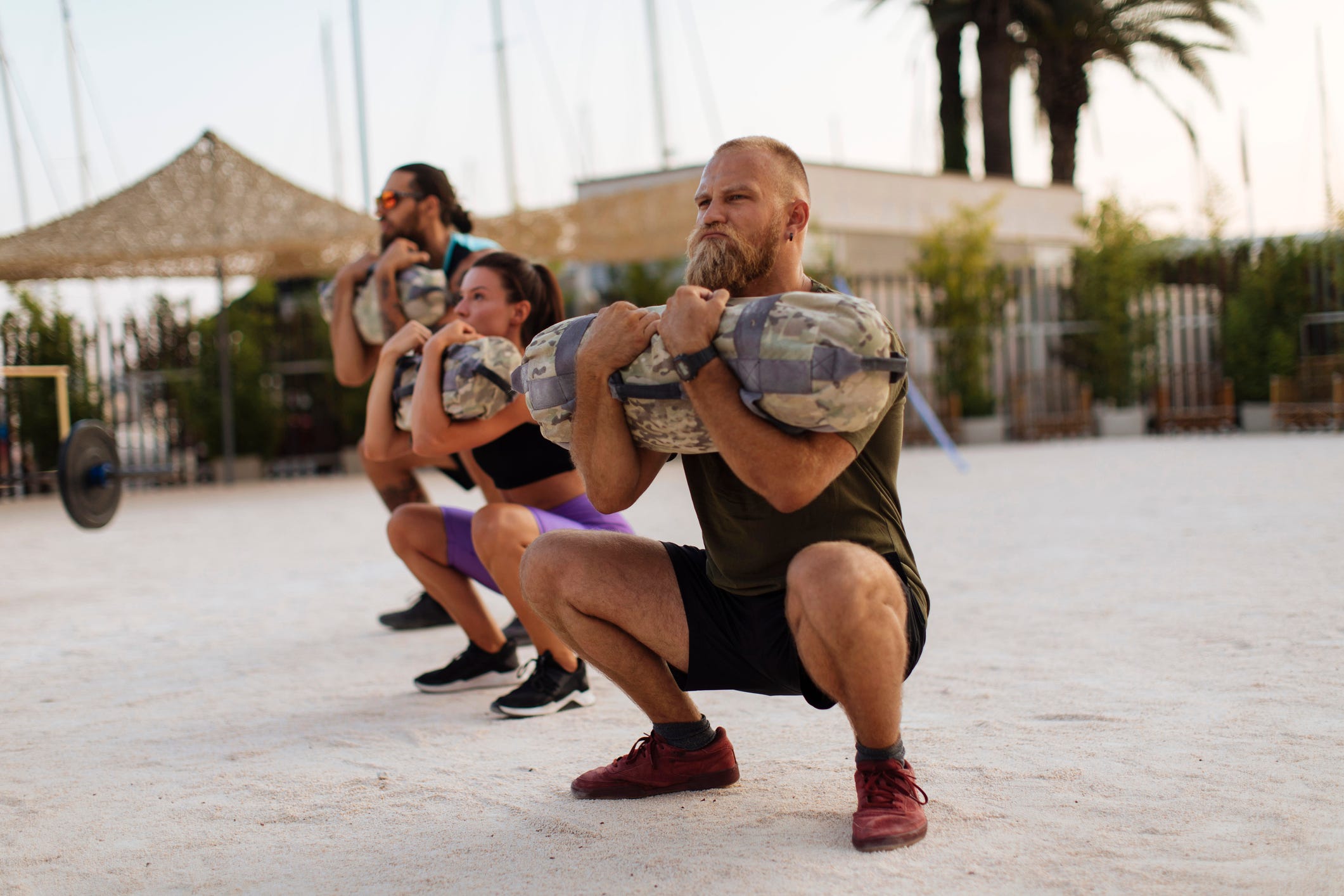 Black sporty young man working out with sandbag while exercises in