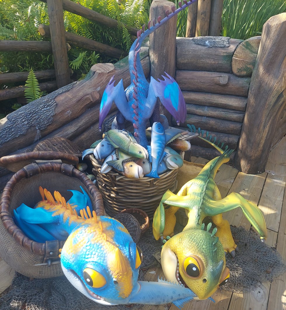 three animatronic baby dragons fight over fish at isle of berk in epic universe
