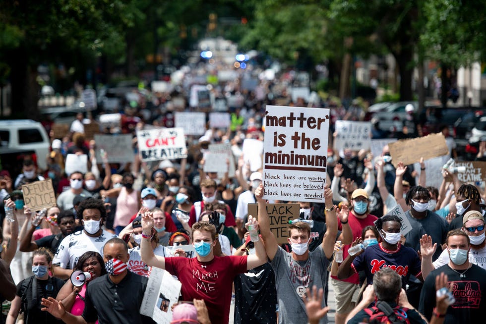 man holding up sign that reads 'matter is the minimum'