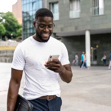 man in a white tshirt walking while looking at his phone