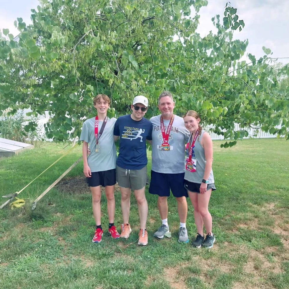 group of four people posing together outdoors wearing medals john donahue how running changed me runner's world
