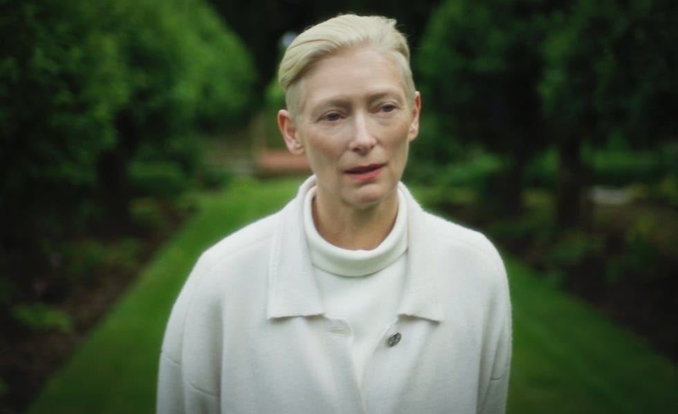 person standing in a garden pathway surrounded by greenery