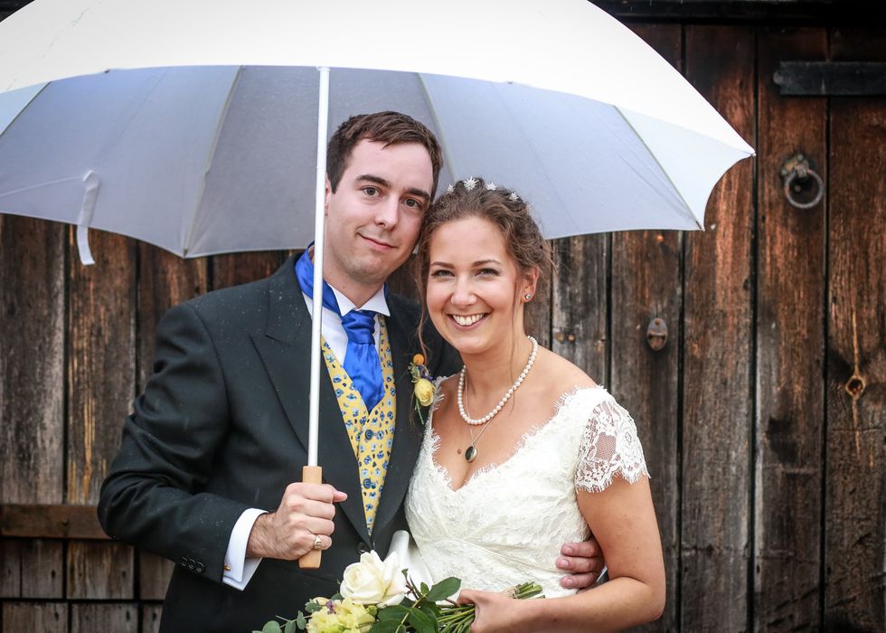 a bride and groom posing under an umbrella