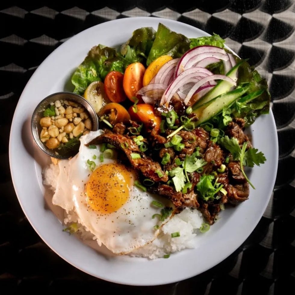 plate of food featuring rice fried egg grilled meat fresh vegetables and peanuts