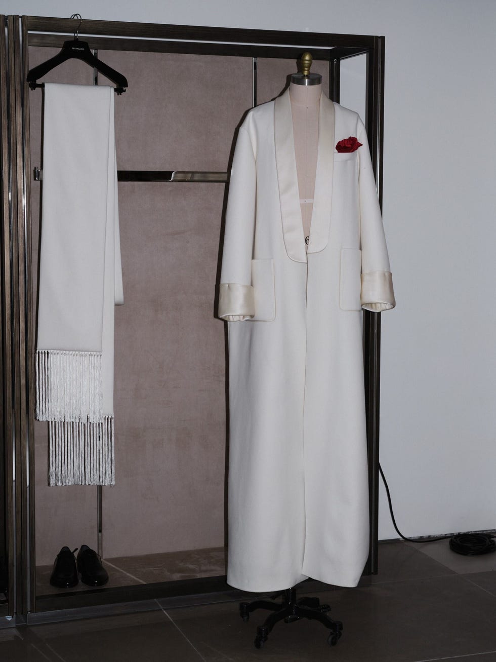 une présentation de mode mettant en vedette un élégant manteau blanc avec un accessoire rose rouge aux côtés d'une écharpe assortie et de chaussures noires