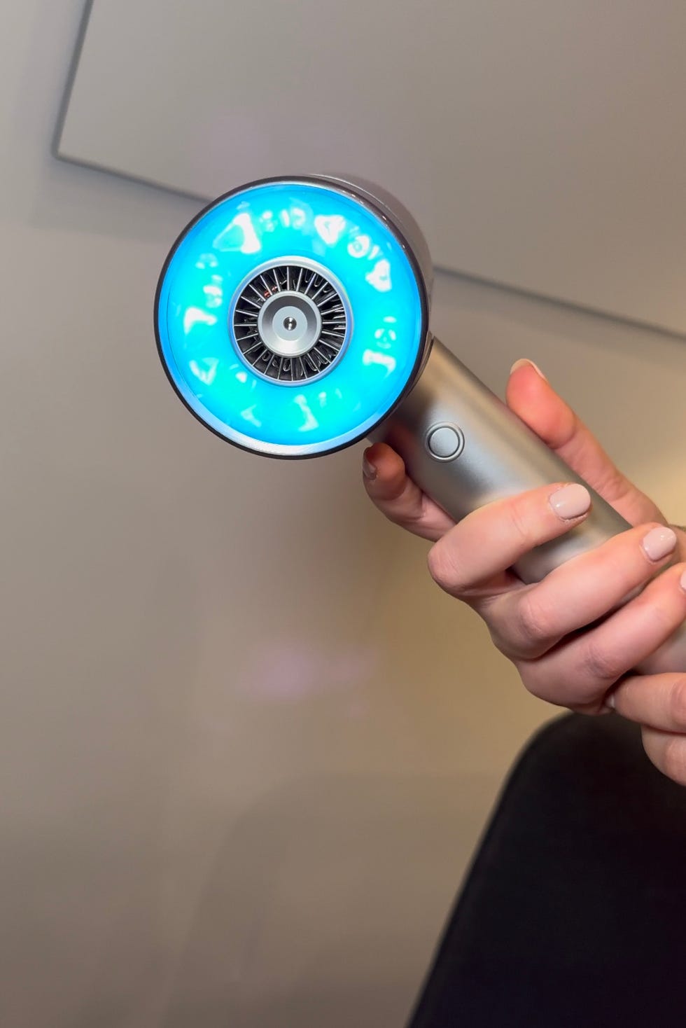 a hand holding a blue and white object with a black circle on it