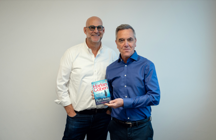 two individuals posing together one holding a book