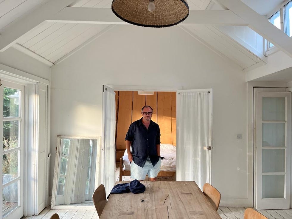 interior of a bright airy room with a table and doorways leading to a bedroom