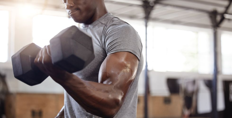 unknown african american athlete lifting dumbbell during bicep curl arm workout in gym strong, fit, active black man training with weight in health and sports club weightlifting exercise routine