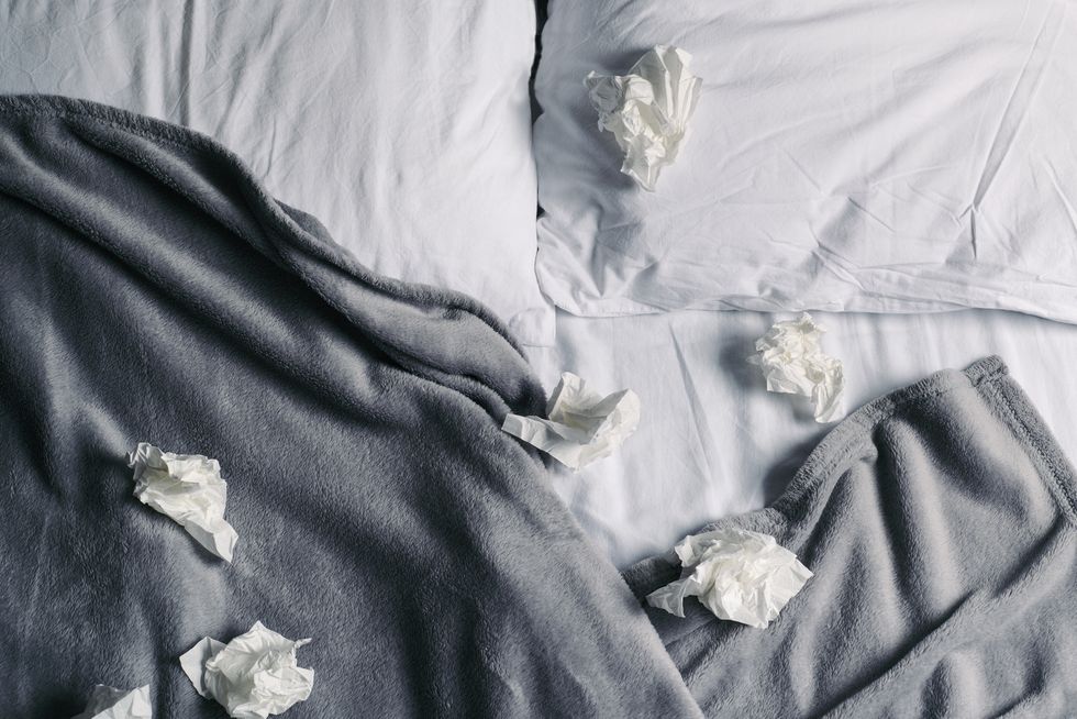unmade bed full of used tissues