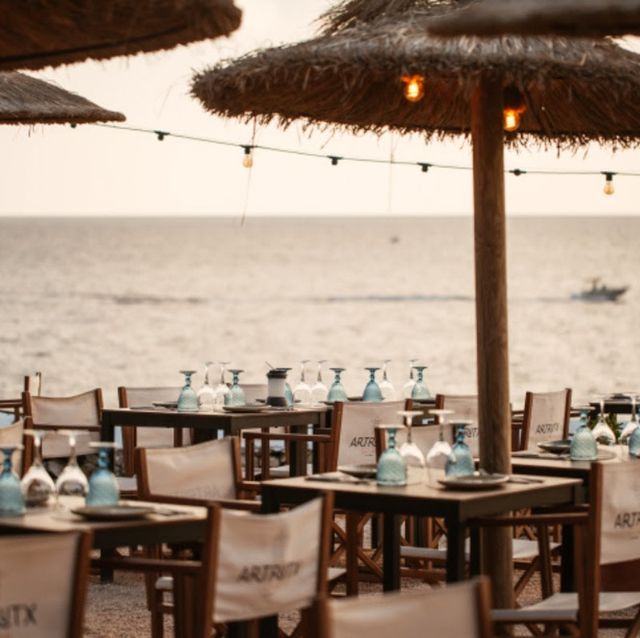 mesas y sillas con sombrilla frente al mar
