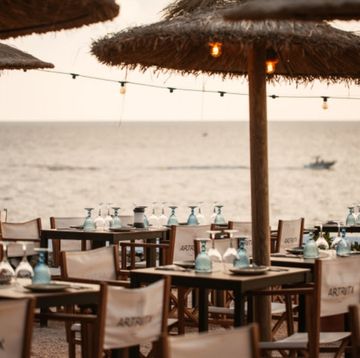 mesas y sillas con sombrilla frente al mar