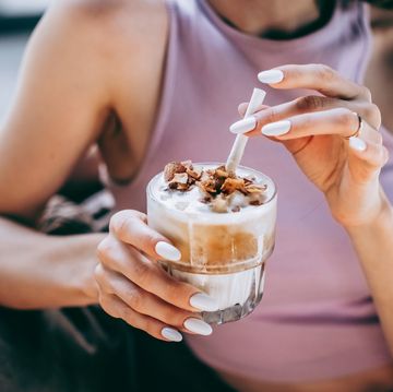 unrecognised young woman enjoing moment and drinking iced coconut coffee with coconut flakes and a white zero waste straw.