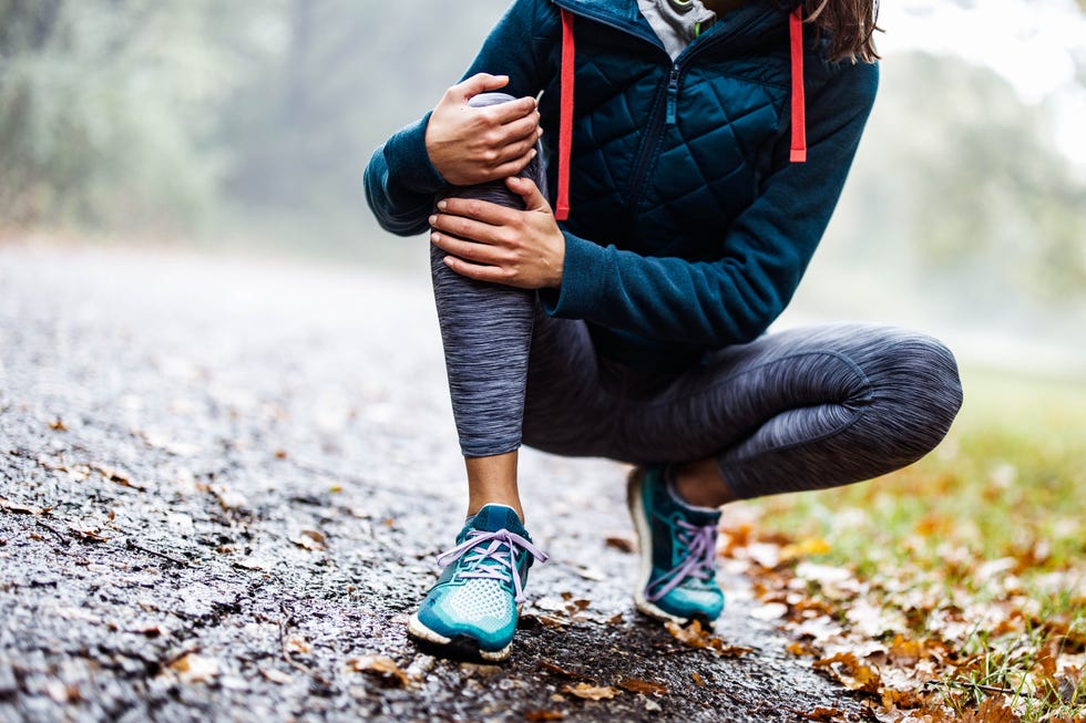 unrecognizable athlete holding her knee in pain at the park