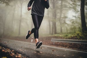 unrecognizable athlete running on misty autumn day in the forest