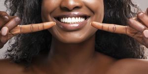 unrecognizable black woman pointing at her healthy white teeth, closeup