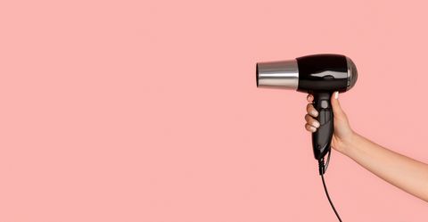 woman holding hair blow dryer on pink background, giving up heat styling your hair for lent