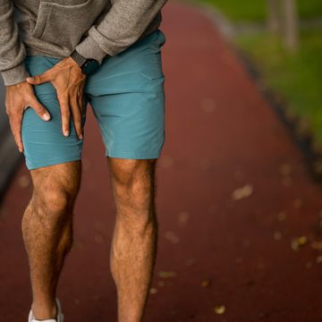 unrecognizable male athlete injured his thigh during outdoor run.