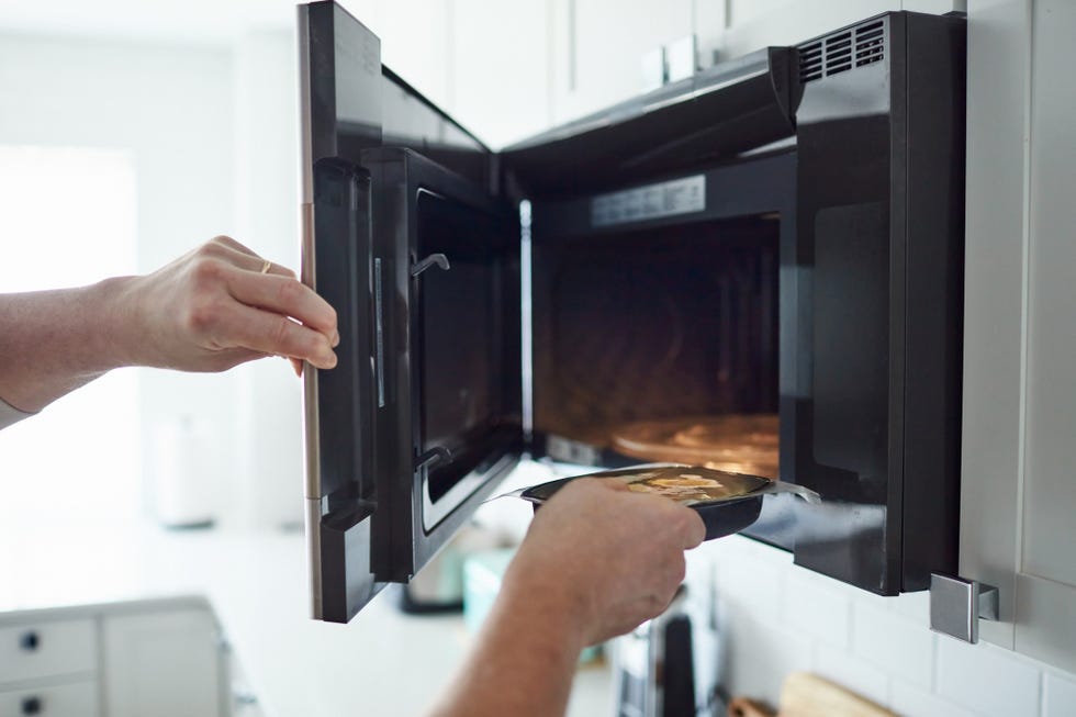 unrecognizable male putting food into a microwave