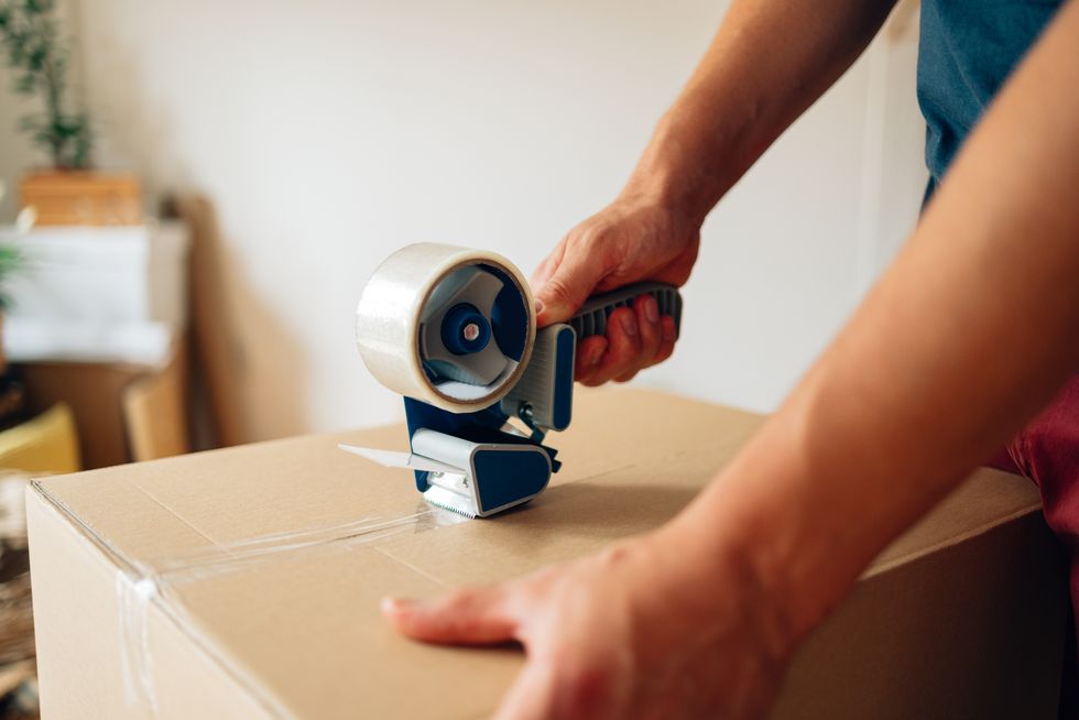 man packing a box with adhesive tape