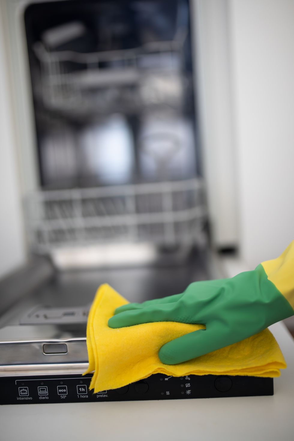 unrecognizable person with cleaning gloves cleaning dishwasher with cleaning cloth focus on the foregroundcopy space