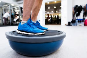 unrecognizable senior man in gym standing on bosu balance ball