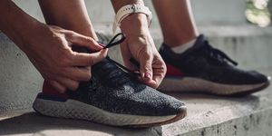 unrecognizable sportswoman tying laces on running sneakers, a close up