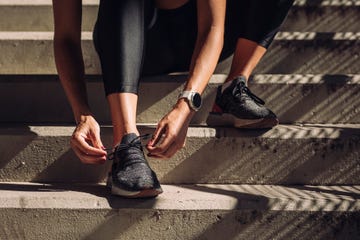 unrecognizable sportswoman tying laces on running sneakers, a close up