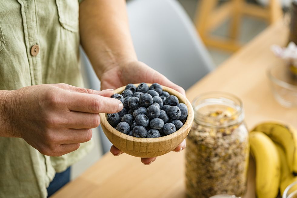 unrecognizable woman eating organic blueberries