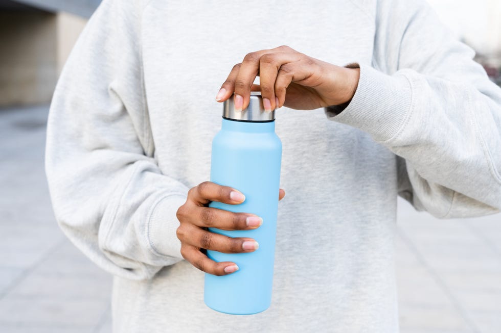 unrecognizable woman opening a bottle of water in the street