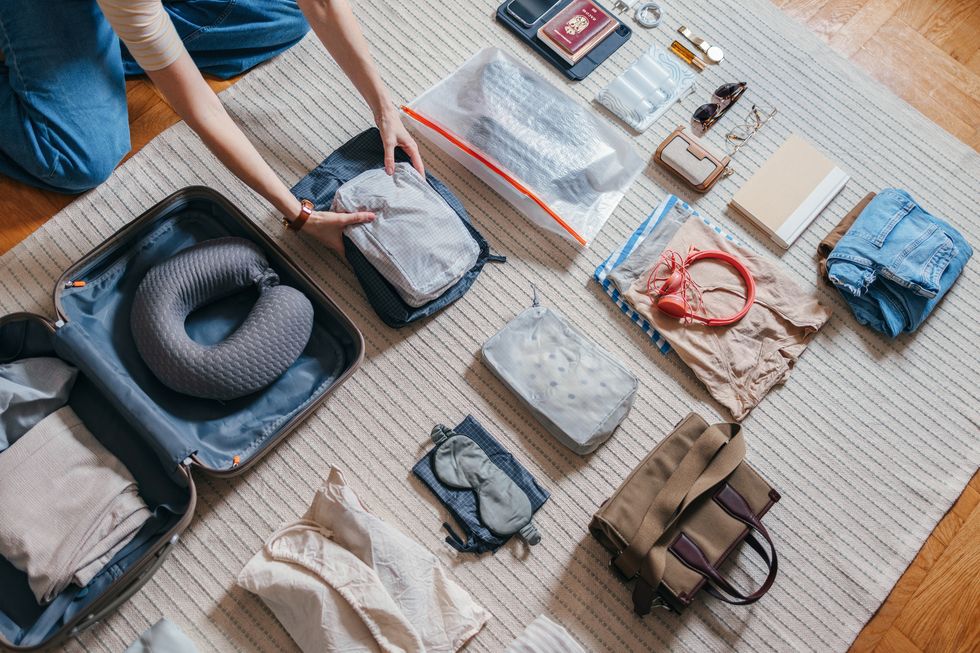 unrecognizable woman packing a suitcase at home