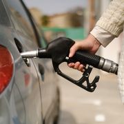 woman holding gas pump nozzle to car gas tank