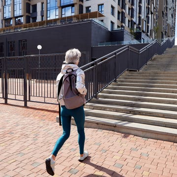 unrecognizable woman walking on street with staircase