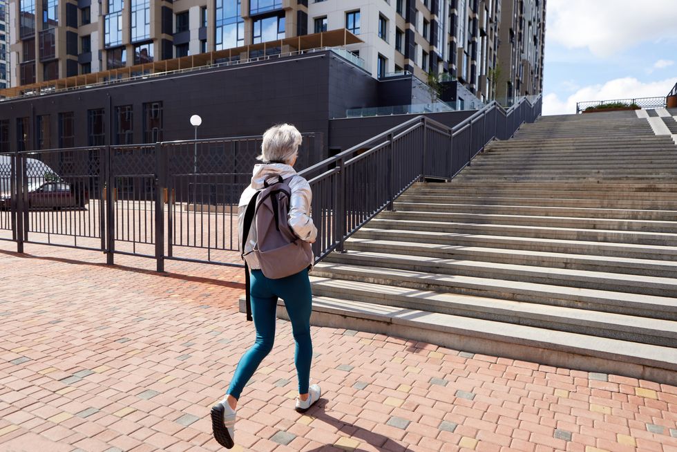 unrecognizable woman walking on street with staircase