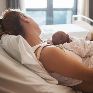 a person in a white dress lying on a bed with a baby