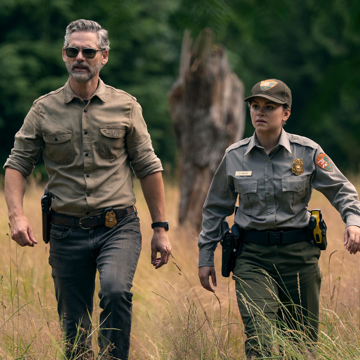 Eric Bana and Lily Santiago in 'Untamed' a man and a woman walk through a field of tall grass cr. ricardo hubbs/netflix © 2025