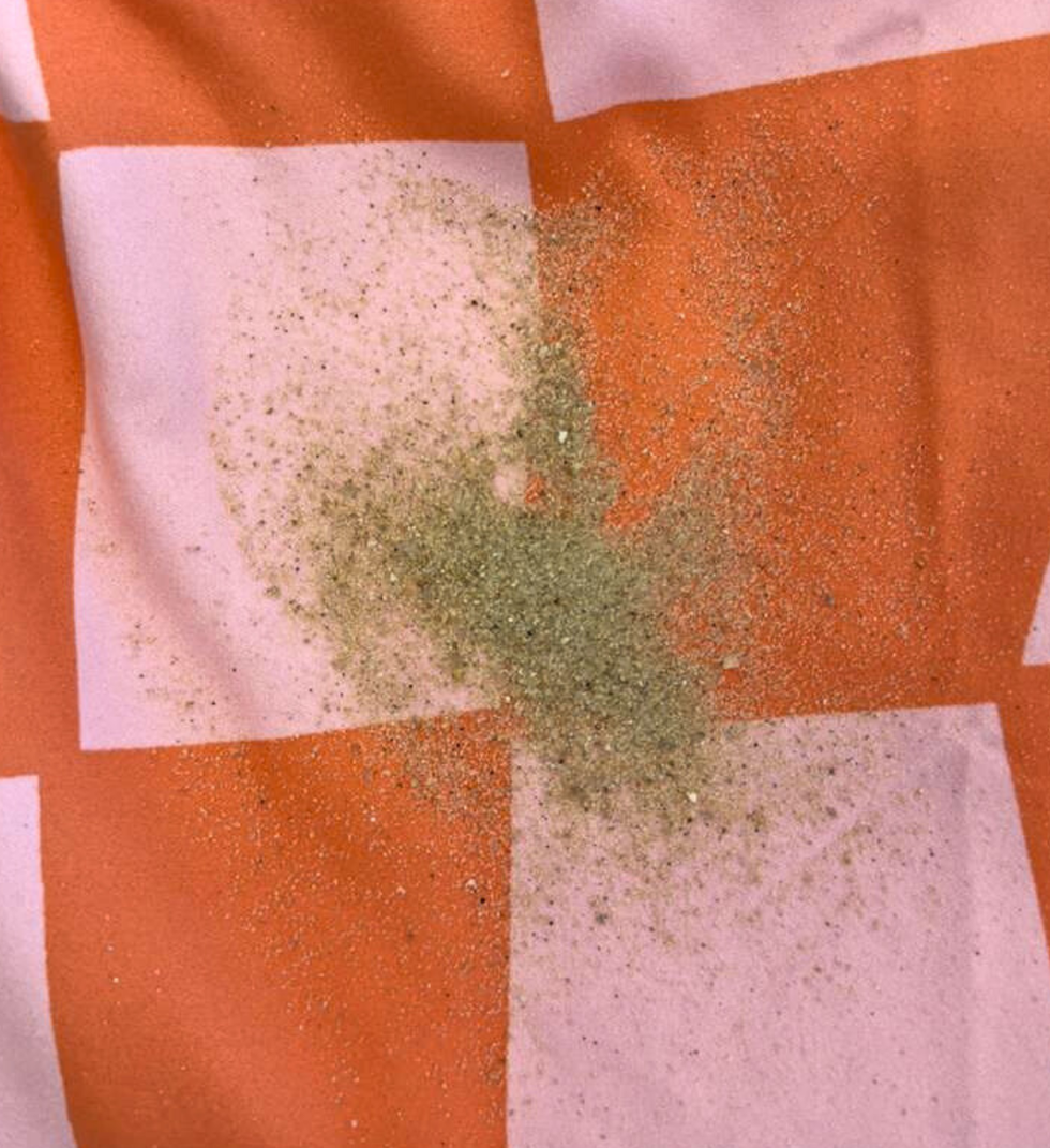 a pink and orange microfiber beach towel with sand on top