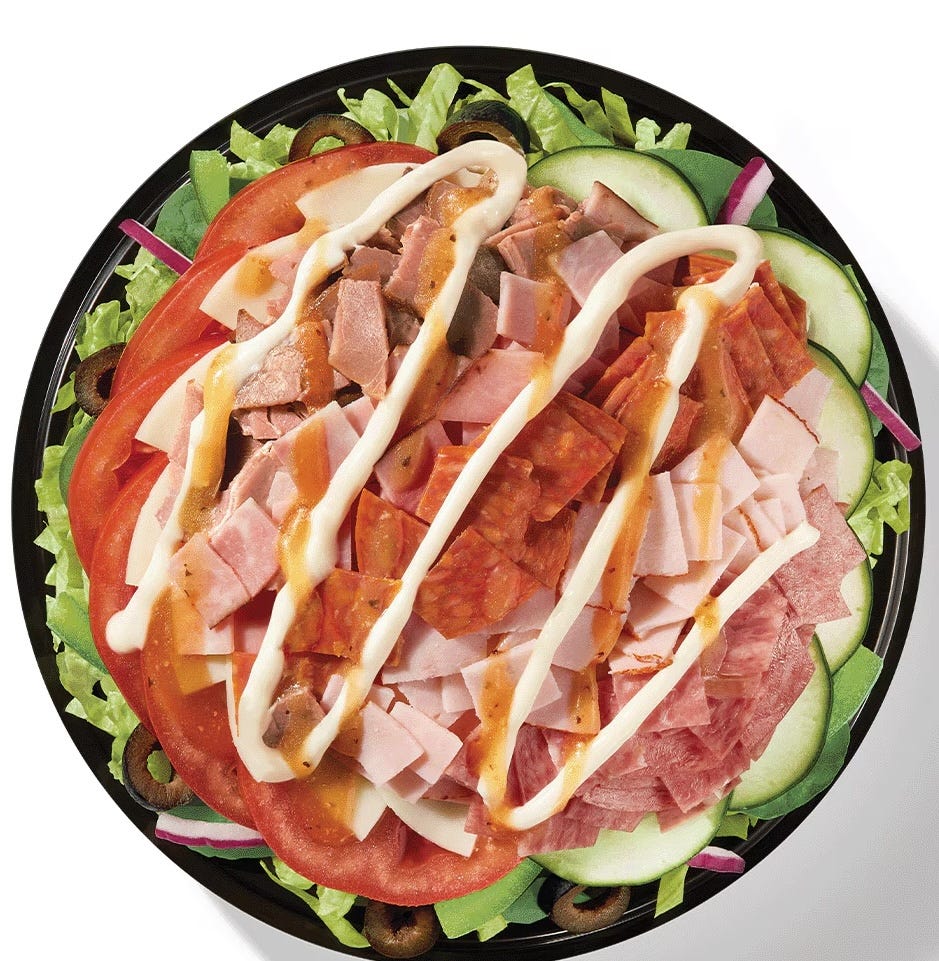 a platter of layered salad with various meats vegetables and dressings