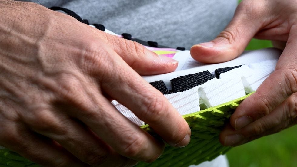 hands holding up a pair of floatzig 1 trainers and examining the sole