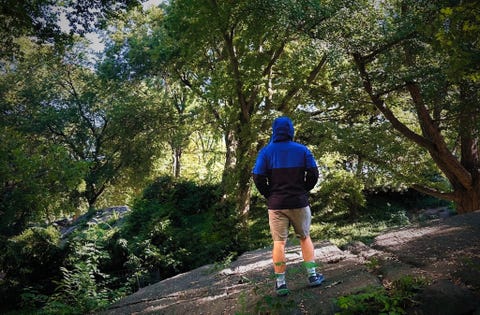 a man modeling a blue and black rain jacket in the woods