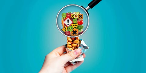 Hand holding a snack bar under a magnifying glass showing various food safety icons and images