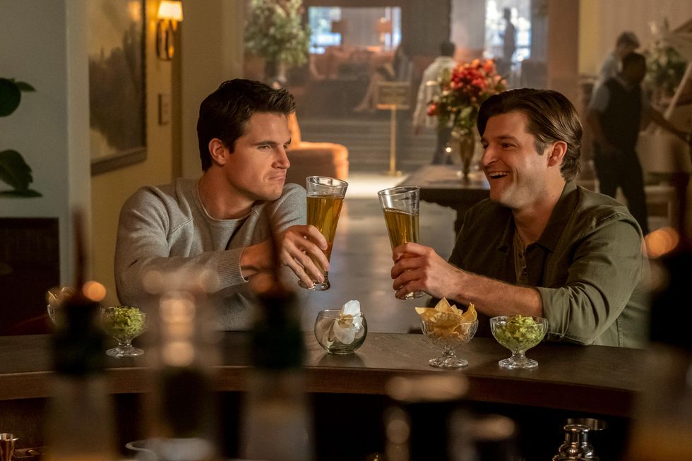 robbie amell as nathan brown in a bar with a friend holding beers, upload