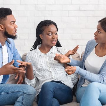 upset afro woman trying to stop friends from quarreling at home