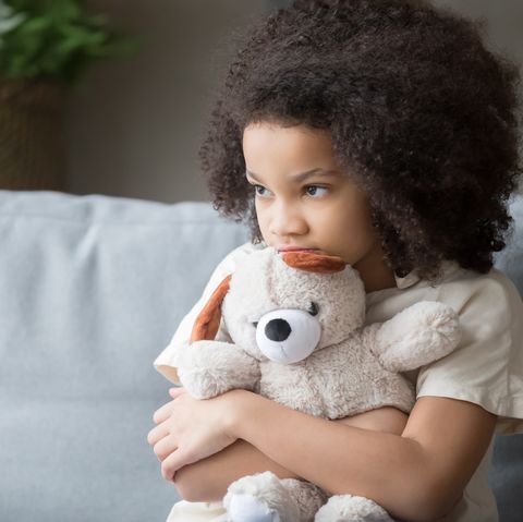 upset lonely african kid girl holding teddy bear looking away