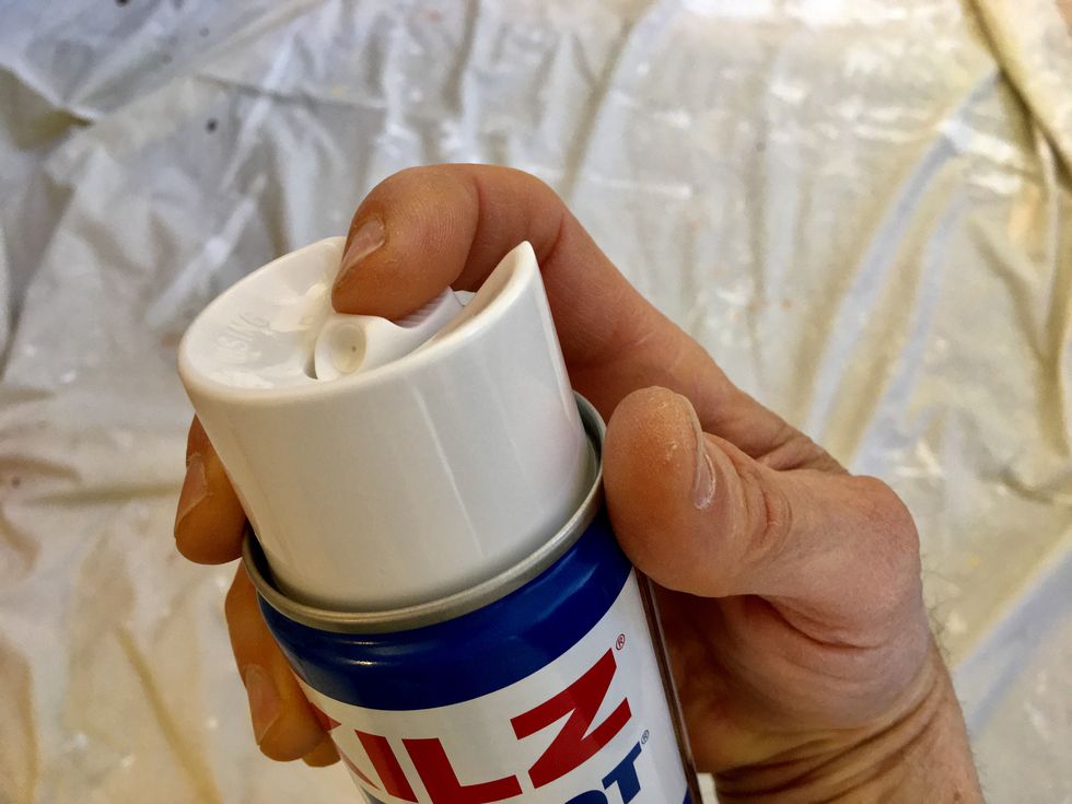 a hand holding a small white container with a white lid