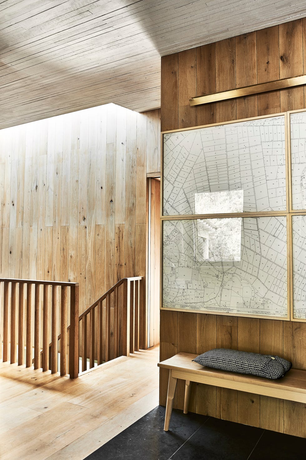 in the hallway, a set of large brass framed maps has been hung together above a bench