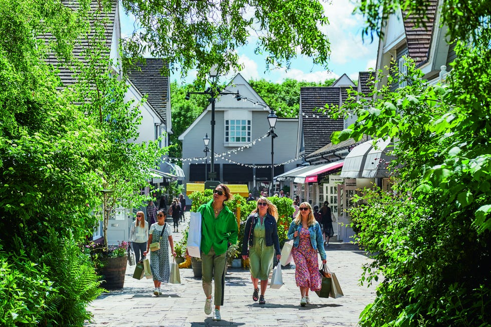 outdoor shopping area with people walking and carrying shopping bags
