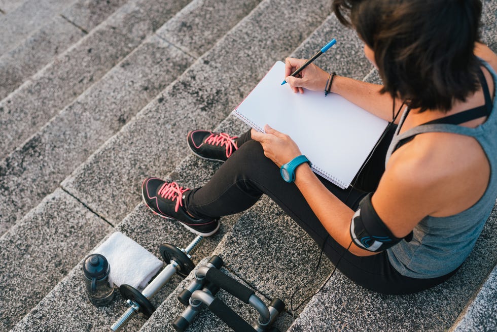 Urban female athlete focusing on her goals writting on notepad