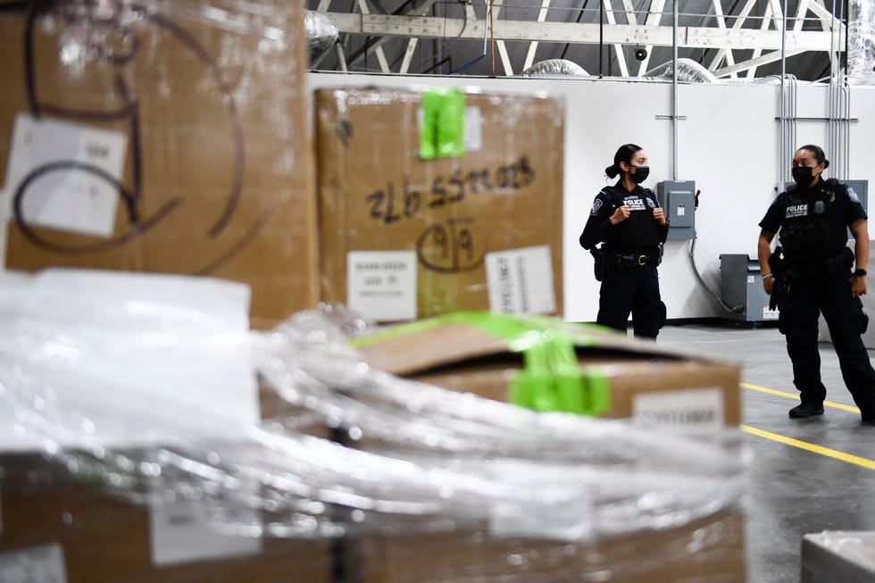 Agenti della dogana e della protezione delle frontiere (CBP) degli Stati Uniti accanto al carico sequestrato per l'ispezione fisica durante la cerimonia di apertura di una stazione di controllo centralizzata dedicata all'aeroporto internazionale di Los Angeles (LAX) con servizi specializzati per la dogana e la protezione delle frontiere (CBP) degli Stati Uniti presso l'aeroporto internazionale di Los Angeles (LAX) il 16 settembre 2021 a Los Angeles, California. La nuova struttura di 3.700 metri quadrati è progettata per accelerare lo screening delle spedizioni e dei carichi di e-commerce, intercettando al contempo merci illecite, tra cui prodotti contraffatti e stupefacenti, attraverso una combinazione di nuove tecnologie di scansione e ispezioni degli agenti della CBP. (foto di Patrick T. Fallon/AFP) (foto di Patrick T. Fallon/AFP tramite Getty Images)