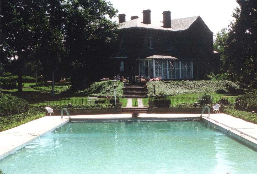 a view of a large brick house from an outdoor pool